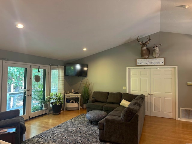 living room with french doors, hardwood / wood-style floors, and vaulted ceiling