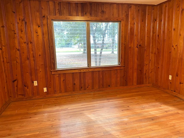 spare room with hardwood / wood-style floors and wooden walls