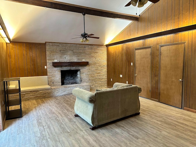 living room with ceiling fan, wood walls, wood-type flooring, and a fireplace