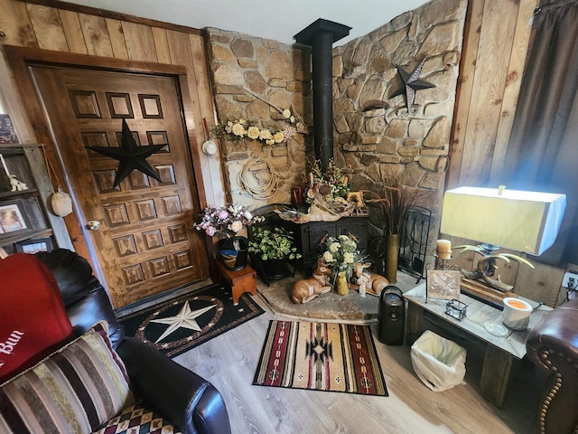 sitting room with wood-type flooring, a wood stove, and wooden walls