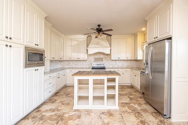 kitchen featuring white cabinetry, a center island, ceiling fan, decorative backsplash, and appliances with stainless steel finishes