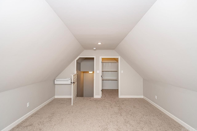 additional living space with vaulted ceiling, light carpet, and an AC wall unit