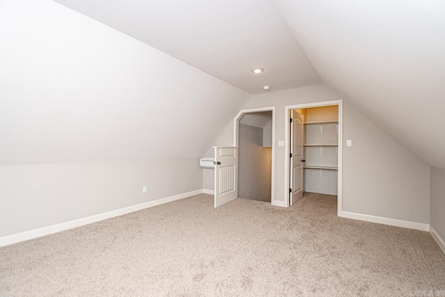 additional living space featuring light colored carpet and vaulted ceiling