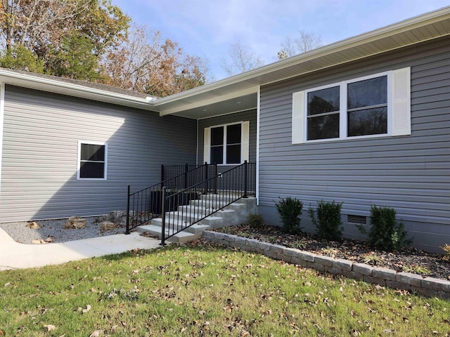 property entrance with crawl space and a lawn