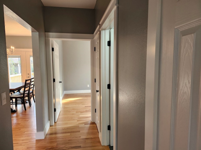 corridor featuring light hardwood / wood-style flooring and a chandelier