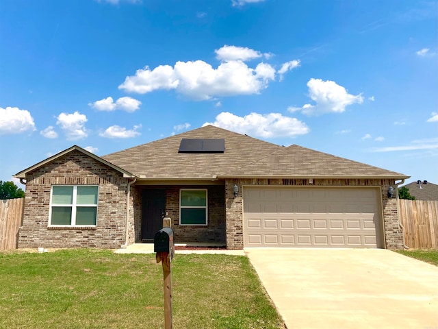 single story home featuring a front yard, solar panels, and a garage