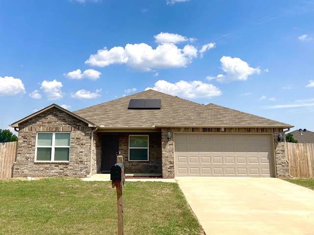 ranch-style house with concrete driveway, an attached garage, a front yard, roof mounted solar panels, and fence