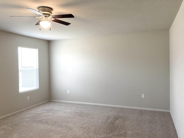 unfurnished room featuring carpet, baseboards, ceiling fan, and a textured ceiling