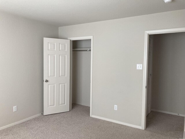 unfurnished bedroom with light colored carpet and a closet