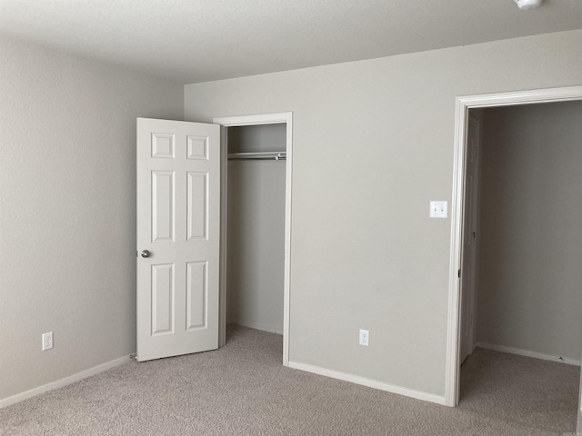 unfurnished bedroom featuring light carpet, baseboards, and a closet