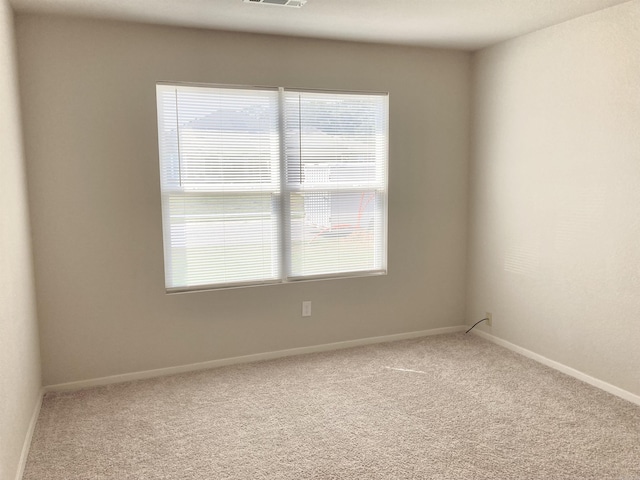 empty room featuring carpet floors, visible vents, and baseboards