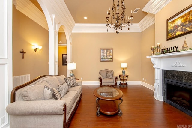 living room featuring a chandelier, a fireplace, dark hardwood / wood-style flooring, and crown molding