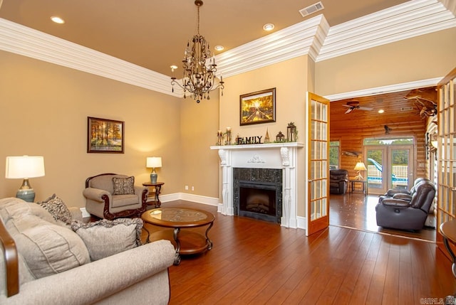 living room featuring a fireplace, crown molding, french doors, ceiling fan with notable chandelier, and dark hardwood / wood-style flooring