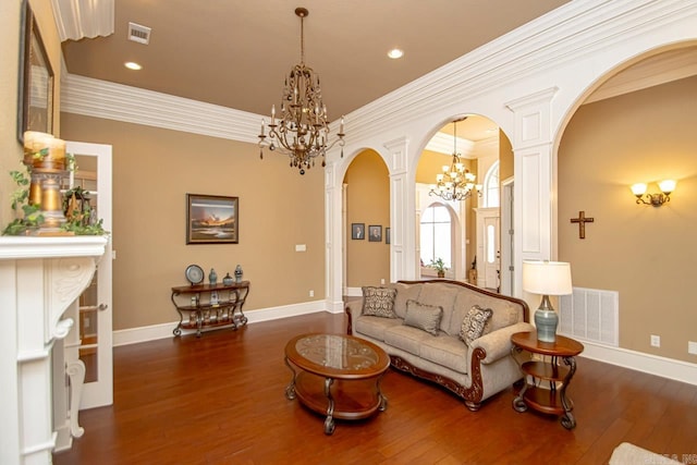 living room with dark wood-type flooring, ornamental molding, and a chandelier