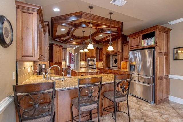 kitchen with a kitchen bar, stainless steel appliances, decorative light fixtures, kitchen peninsula, and sink