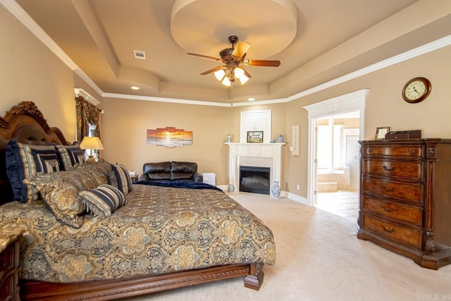 bedroom with carpet, a tray ceiling, crown molding, connected bathroom, and ceiling fan