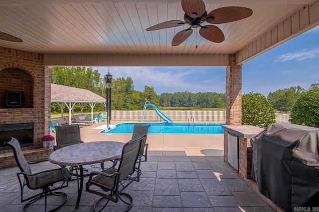 view of patio with a fenced in pool, grilling area, and ceiling fan