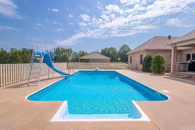 view of pool with a water slide, a diving board, and a patio