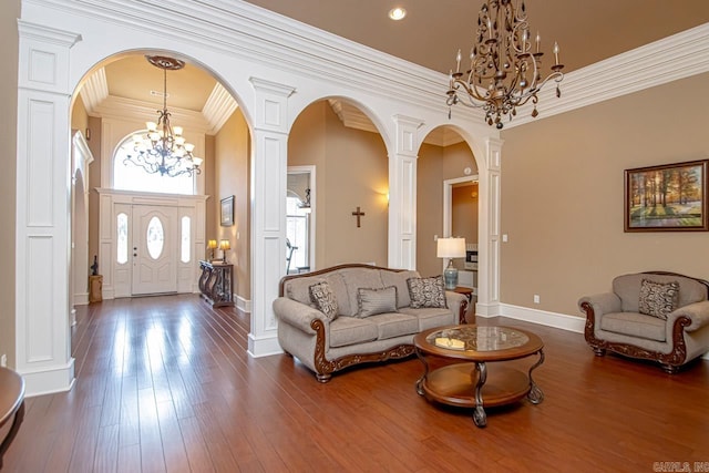 living room featuring a chandelier, ornamental molding, dark hardwood / wood-style flooring, and ornate columns