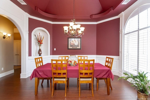 dining room with a tray ceiling, dark wood-type flooring, a wealth of natural light, and an inviting chandelier