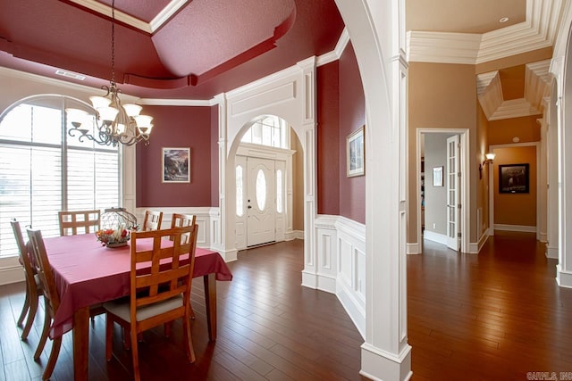 dining room featuring a high ceiling, a notable chandelier, crown molding, a textured ceiling, and dark hardwood / wood-style floors