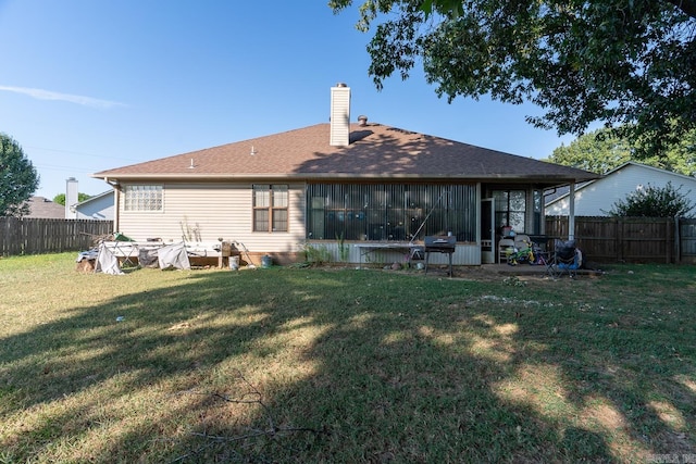 back of house featuring a chimney, fence, and a lawn