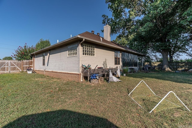 rear view of house featuring a fenced backyard, a chimney, and a yard