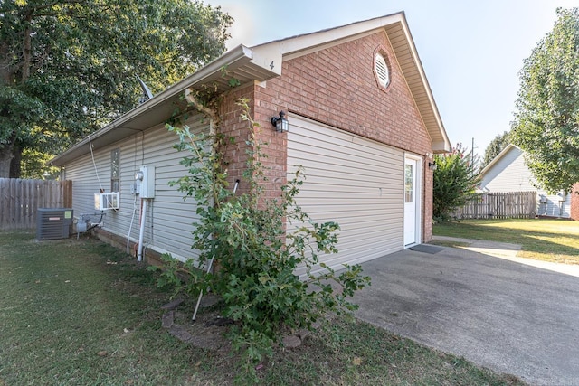 view of side of home with brick siding, a yard, a patio area, fence, and a garage