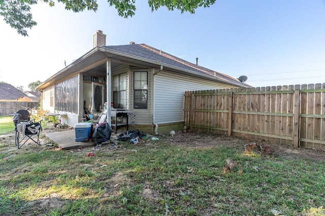 view of side of property featuring fence, a chimney, and a lawn