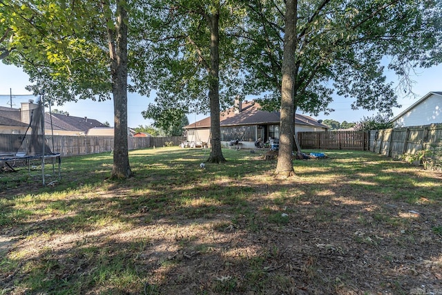 view of yard featuring a trampoline and a fenced backyard