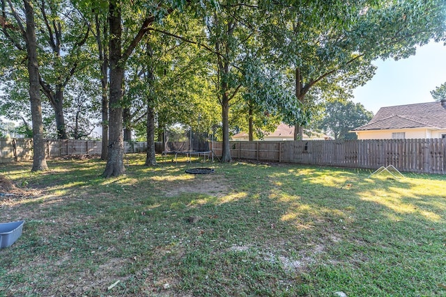 view of yard with a trampoline and a fenced backyard