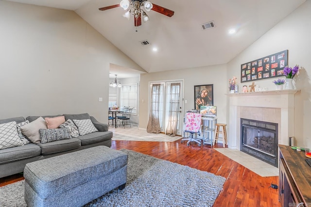 living room featuring a fireplace, visible vents, wood finished floors, and ceiling fan with notable chandelier