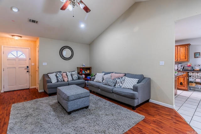 living room featuring dark wood-style floors, lofted ceiling, visible vents, and a ceiling fan