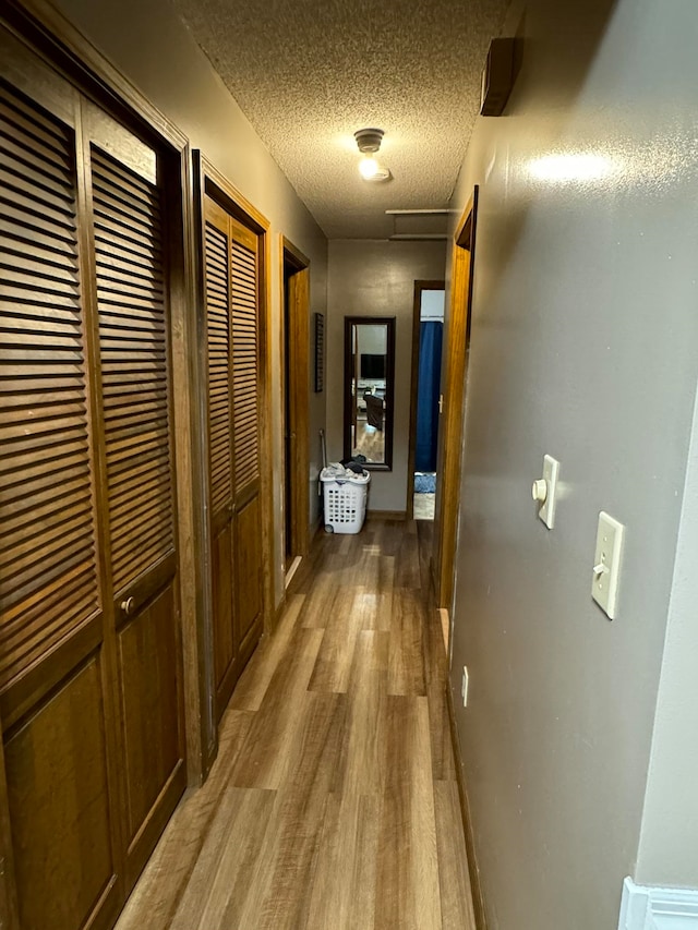 hallway with a textured ceiling and hardwood / wood-style floors