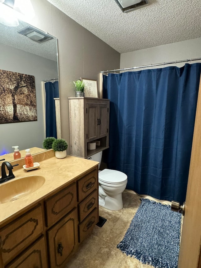 bathroom with a textured ceiling, vanity, toilet, and tile patterned floors