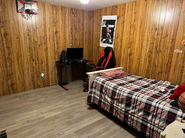 bedroom with wood-type flooring and wooden walls