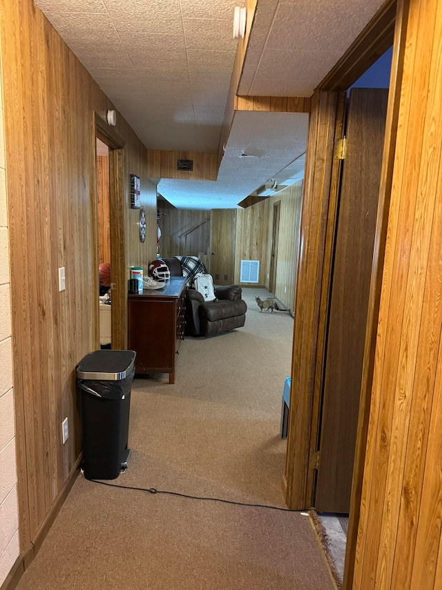 corridor featuring carpet and wood walls