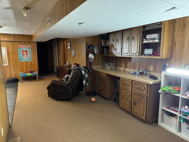 interior space featuring light colored carpet, wooden walls, and built in desk