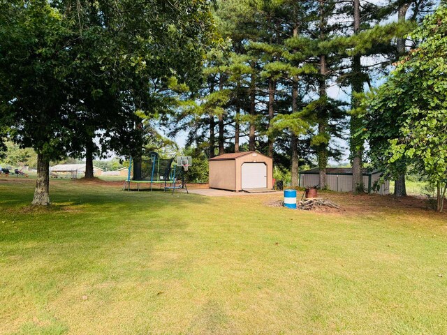 view of yard with an outbuilding, a garage, and a trampoline