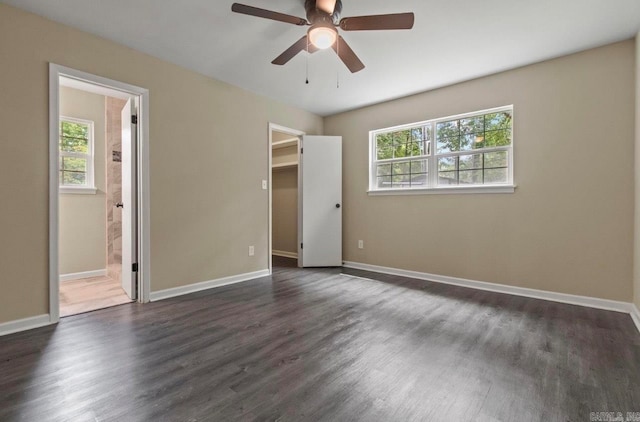 empty room with dark wood-type flooring, plenty of natural light, and ceiling fan