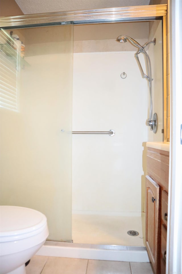 full bath with a stall shower, tile patterned flooring, vanity, and toilet