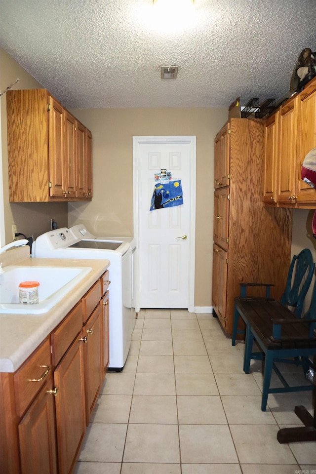 washroom featuring cabinet space, washing machine and dryer, light tile patterned floors, and a sink