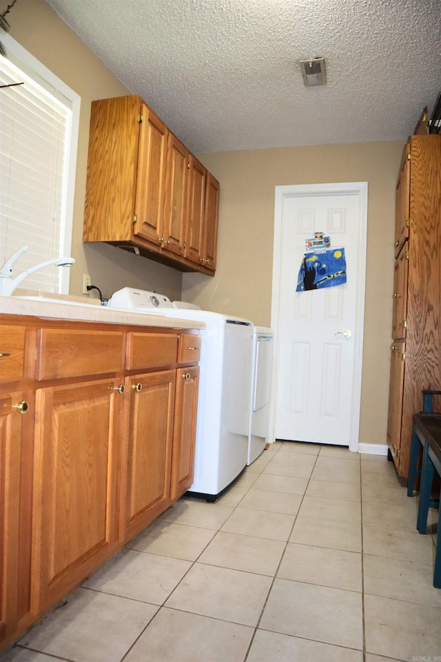 laundry area featuring cabinet space, light tile patterned floors, separate washer and dryer, and a textured ceiling