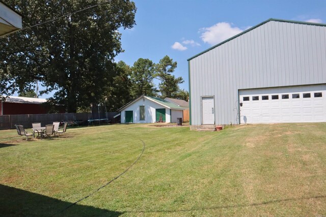 view of yard featuring entry steps, a trampoline, fence, and a detached garage