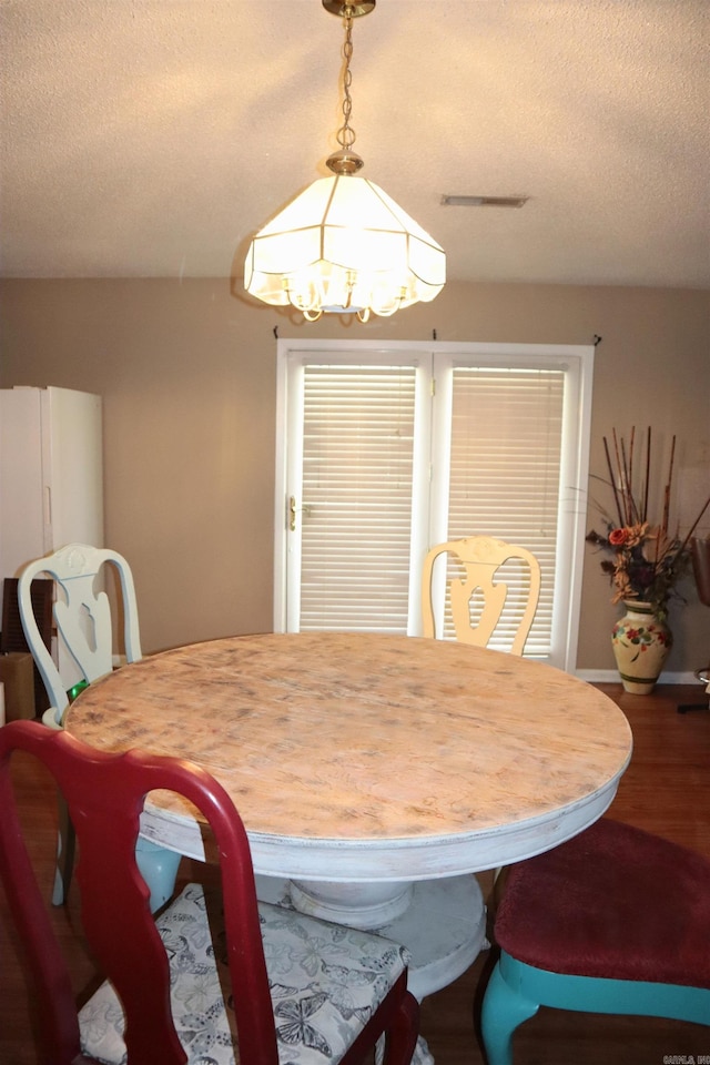 dining area featuring visible vents, a textured ceiling, and wood finished floors