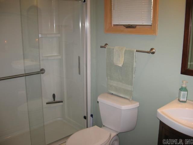 bathroom featuring vanity, toilet, and a shower with shower door