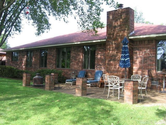 back of house featuring a lawn and a patio area