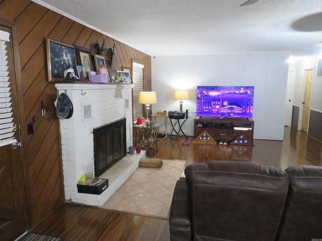 living room featuring wooden walls, a fireplace, wood-type flooring, and a textured ceiling