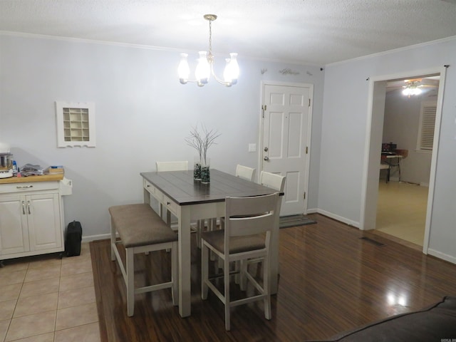 dining room with ornamental molding, light hardwood / wood-style flooring, a textured ceiling, and ceiling fan with notable chandelier