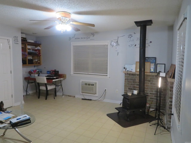 interior space featuring an AC wall unit, a textured ceiling, a wood stove, and ceiling fan